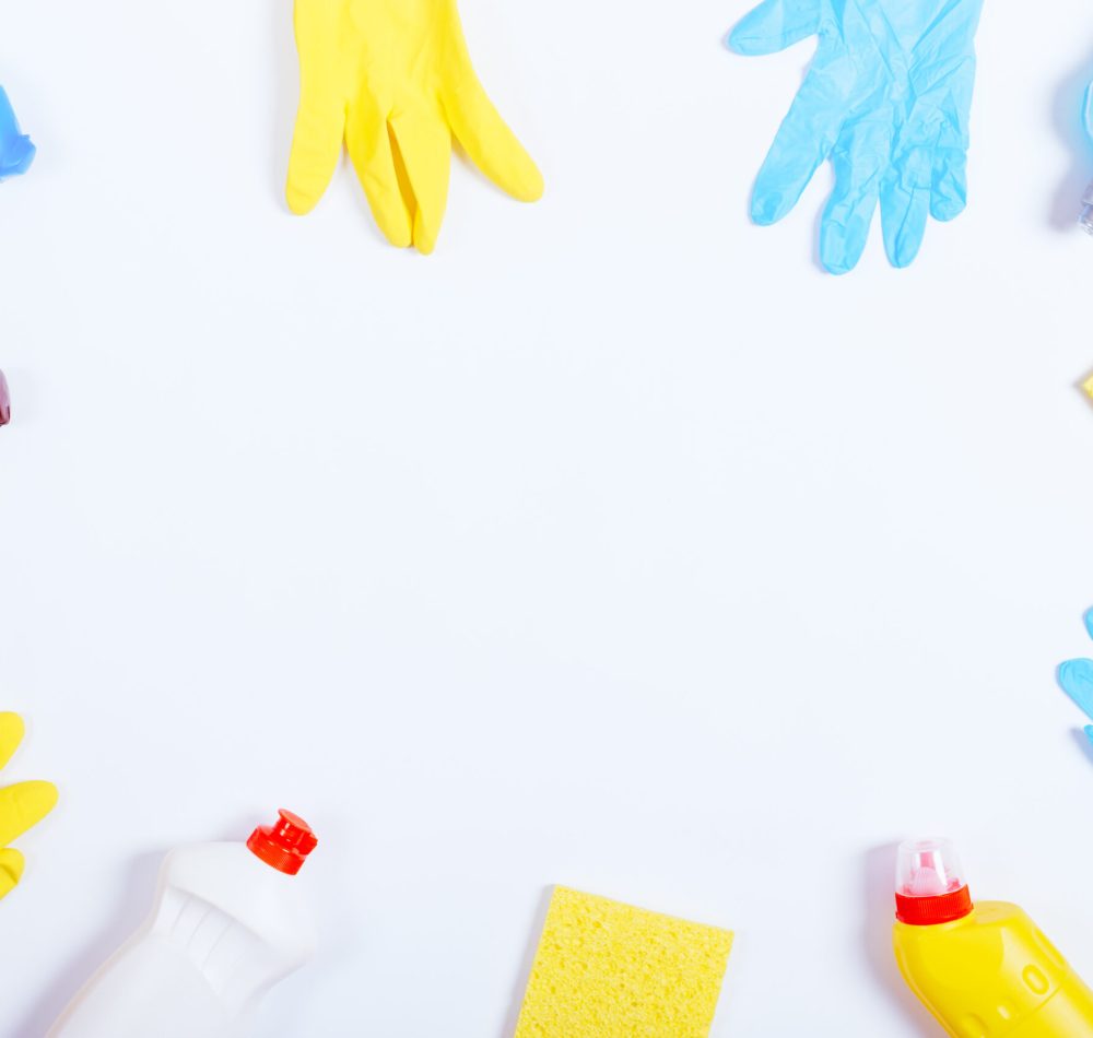 Rubber gloves, sponges and bottles of cleaning fluids on a white background, place for text, top view